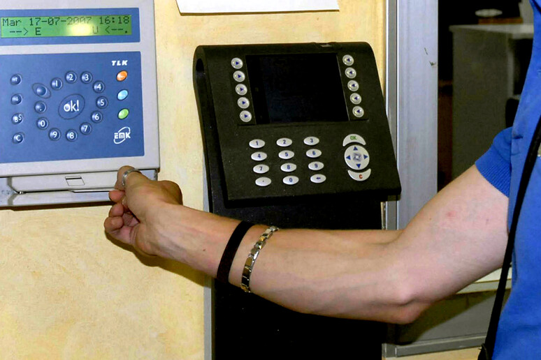 Un impiegato tibra il cartellino di presenza al lavoro in una immagine d 'archivio - RIPRODUZIONE RISERVATA