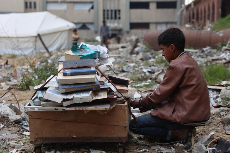 Palestinesi sfollati raccolgono libri dall'università distrutta per bruciarli e cucinare cibo