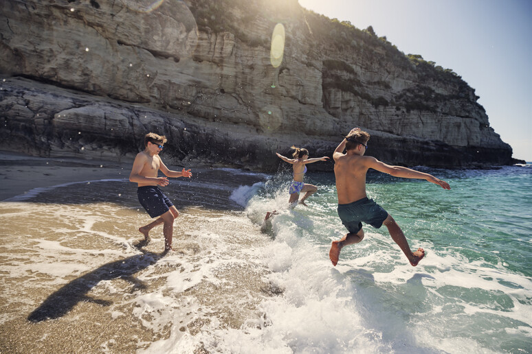 La gioia di tuffarsi al mare di tre giovani foto iStock. - RIPRODUZIONE RISERVATA